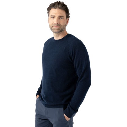 A man with dark hair and a beard stands casually with his hands in his pockets. He is wearing the Cozy Earth Men's Crewneck Sweater in navy blue, paired with gray pants. He looks at the camera with a neutral expression, set against a plain white background. |Color:Eclipse