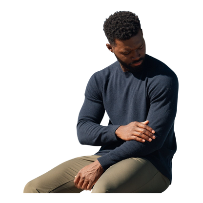 A man with dark hair and a beard stands casually with his hands in his pockets. He is wearing the Cozy Earth Men's Crewneck Sweater in navy blue, paired with gray pants. He looks at the camera with a neutral expression, set against a plain white background. |Color:Eclipse