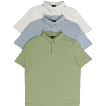 A person with short, light brown hair is wearing the Men's Everyday Polo by Cozy Earth in a light gray shade, paired with light beige pants. They are standing and slightly looking over their left shoulder with a neutral expression against a plain white background. |Color:Stone