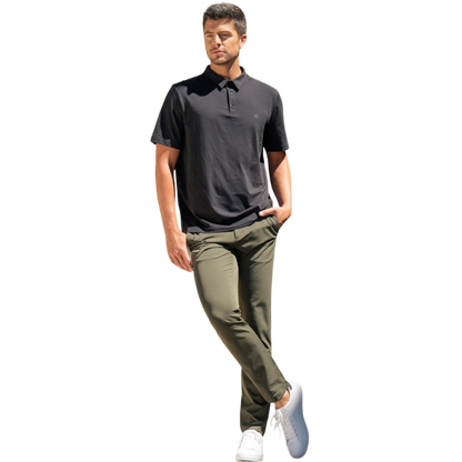 A person with short, light brown hair is wearing the Men's Everyday Polo by Cozy Earth in a light gray shade, paired with light beige pants. They are standing and slightly looking over their left shoulder with a neutral expression against a plain white background. |Color:Stone