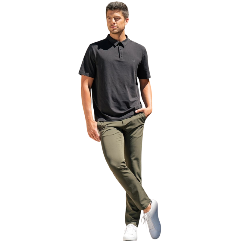 A person with short, light brown hair is wearing the Men's Everyday Polo by Cozy Earth in a light gray shade, paired with light beige pants. They are standing and slightly looking over their left shoulder with a neutral expression against a plain white background. |Color:Stone