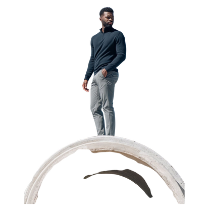 A man with dark hair and a short beard is wearing a navy blue Men's Quarter Zip Sweater from Cozy Earth paired with beige pants. He stands with his hands in his pockets against a plain white background, looking to his right with a slight smile. |Color:Eclipse