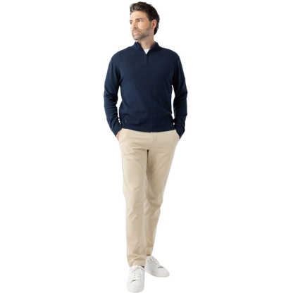 A man with dark hair and a short beard is wearing a navy blue Men's Quarter Zip Sweater from Cozy Earth paired with beige pants. He stands with his hands in his pockets against a plain white background, looking to his right with a slight smile. |Color:Eclipse