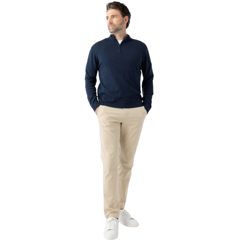 A man with dark hair and a short beard is wearing a navy blue Men's Quarter Zip Sweater from Cozy Earth paired with beige pants. He stands with his hands in his pockets against a plain white background, looking to his right with a slight smile. |Color:Eclipse