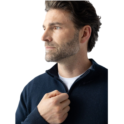 A man with dark hair and a short beard is wearing a navy blue Men's Quarter Zip Sweater from Cozy Earth paired with beige pants. He stands with his hands in his pockets against a plain white background, looking to his right with a slight smile. |Color:Eclipse