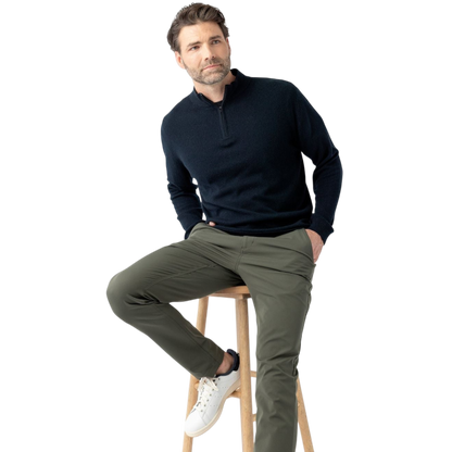 A man with dark hair and a short beard is wearing a navy blue Men's Quarter Zip Sweater from Cozy Earth paired with beige pants. He stands with his hands in his pockets against a plain white background, looking to his right with a slight smile. |Color:Eclipse