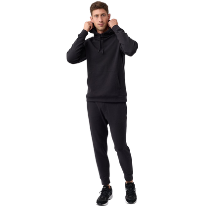 A person wearing the Men's StretchTech Hoodie from Cozy Earth, paired with matching gray pants, stands against a plain white background. The hoodie features drawstrings and a front pocket. The individual is looking forward with a neutral expression. |Color:Coal Heather