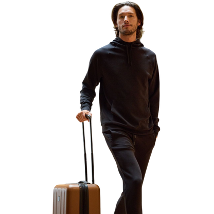 A person wearing the Men's StretchTech Hoodie from Cozy Earth, paired with matching gray pants, stands against a plain white background. The hoodie features drawstrings and a front pocket. The individual is looking forward with a neutral expression. |Color:Coal Heather