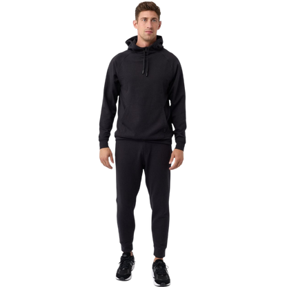 A person wearing the Men's StretchTech Hoodie from Cozy Earth, paired with matching gray pants, stands against a plain white background. The hoodie features drawstrings and a front pocket. The individual is looking forward with a neutral expression. |Color:Coal Heather