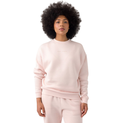 A person with curly hair models the Cozy Earth Women's CityScape Crewneck and matching pants in light pink against a plain white backdrop. |Color:Peony