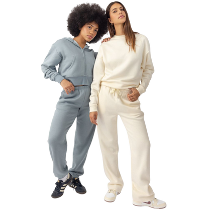 A person with curly hair models the Cozy Earth Women's CityScape Crewneck and matching pants in light pink against a plain white backdrop. |Color:Peony