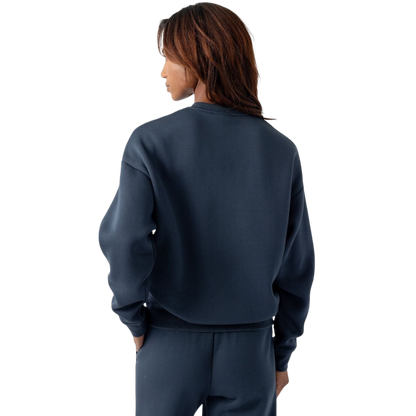 A person with curly hair models the Cozy Earth Women's CityScape Crewneck and matching pants in light pink against a plain white backdrop. |Color:Peony