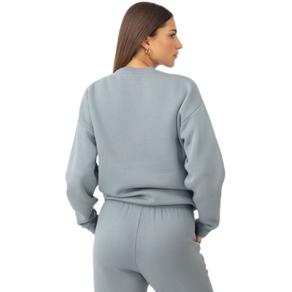A person with curly hair models the Cozy Earth Women's CityScape Crewneck and matching pants in light pink against a plain white backdrop. |Color:Peony