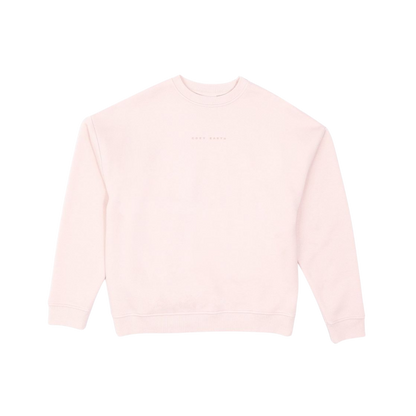 A person with curly hair models the Cozy Earth Women's CityScape Crewneck and matching pants in light pink against a plain white backdrop. |Color:Peony