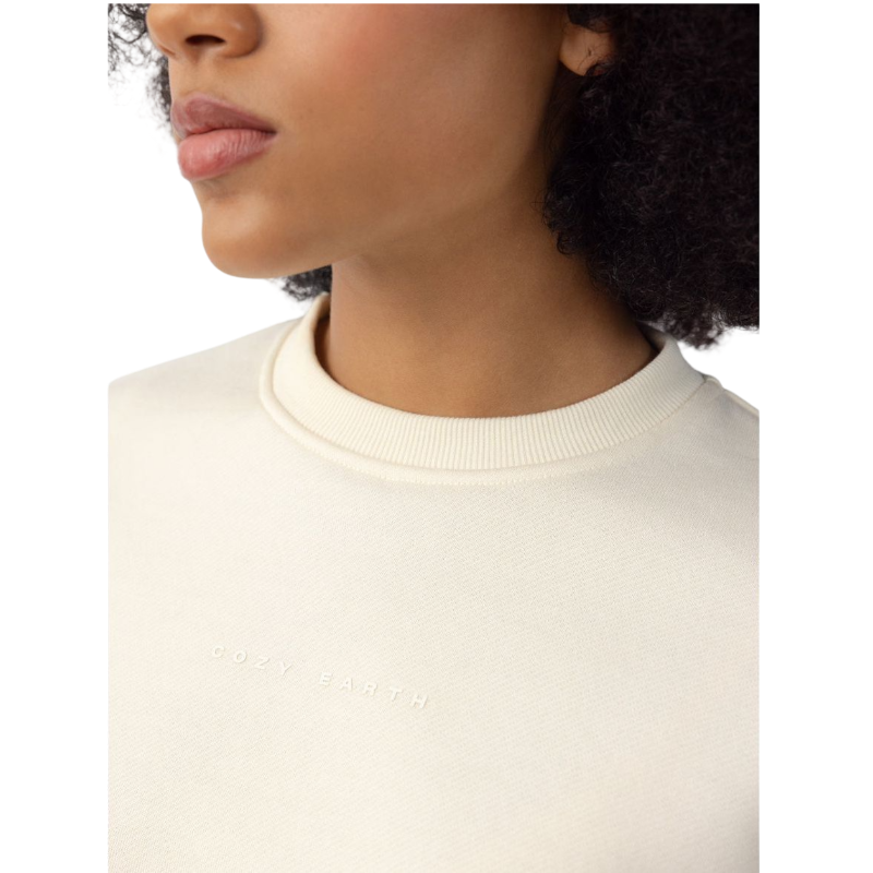 A person with curly hair models the Cozy Earth Women's CityScape Crewneck and matching pants in light pink against a plain white backdrop. |Color:Peony