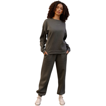 A person with curly hair models the Cozy Earth Women's CityScape Crewneck and matching pants in light pink against a plain white backdrop. |Color:Peony