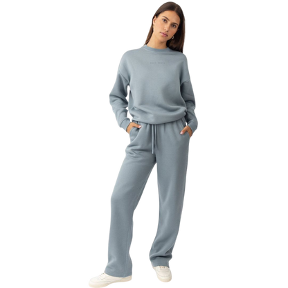 A person with curly hair models the Cozy Earth Women's CityScape Crewneck and matching pants in light pink against a plain white backdrop. |Color:Peony