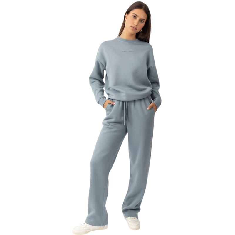 A person with curly hair models the Cozy Earth Women's CityScape Crewneck and matching pants in light pink against a plain white backdrop. |Color:Peony