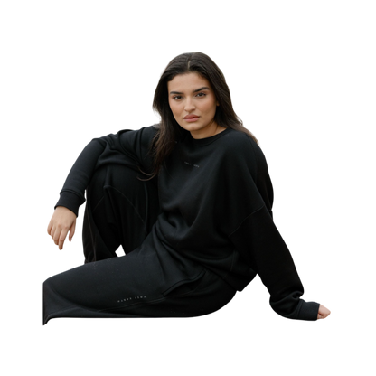 A person with curly hair models the Cozy Earth Women's CityScape Crewneck and matching pants in light pink against a plain white backdrop. |Color:Peony