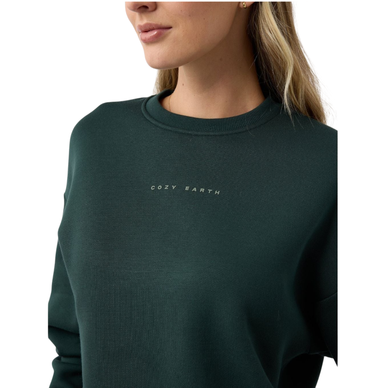 A person with curly hair models the Cozy Earth Women's CityScape Crewneck and matching pants in light pink against a plain white backdrop. |Color:Peony