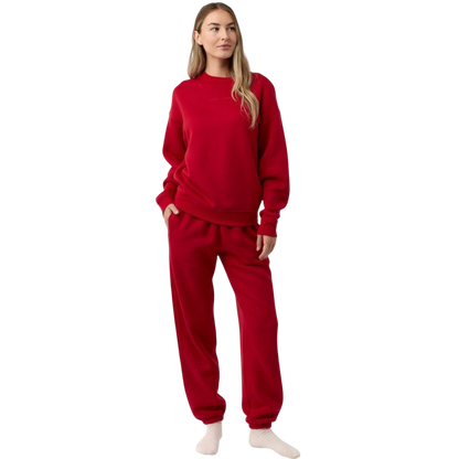A person with curly hair models the Cozy Earth Women's CityScape Crewneck and matching pants in light pink against a plain white backdrop. |Color:Peony