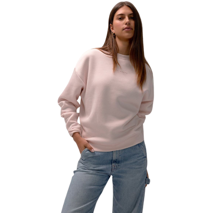 A person with curly hair models the Cozy Earth Women's CityScape Crewneck and matching pants in light pink against a plain white backdrop. |Color:Peony
