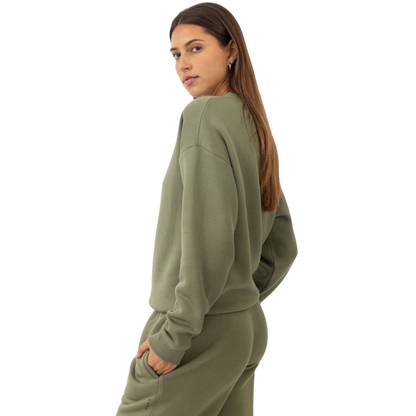 A person with curly hair models the Cozy Earth Women's CityScape Crewneck and matching pants in light pink against a plain white backdrop. |Color:Peony