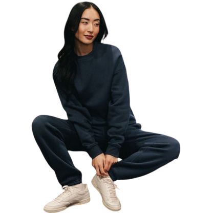 A person with curly hair models the Cozy Earth Women's CityScape Crewneck and matching pants in light pink against a plain white backdrop. |Color:Peony