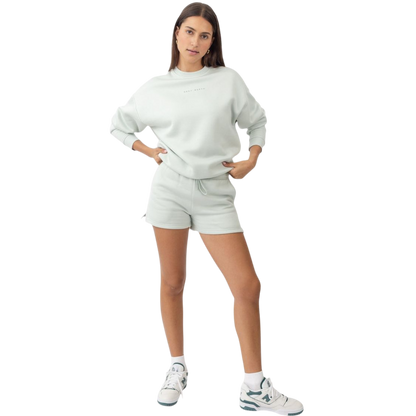 A person with curly hair models the Cozy Earth Women's CityScape Crewneck and matching pants in light pink against a plain white backdrop. |Color:Peony