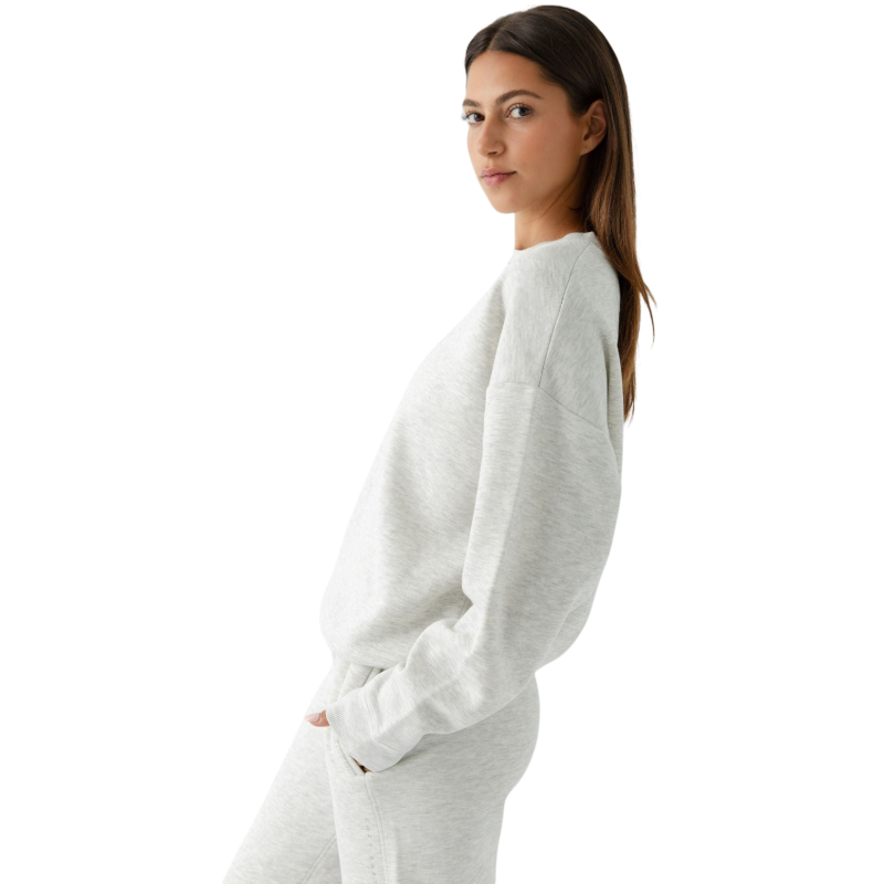 A person with curly hair models the Cozy Earth Women's CityScape Crewneck and matching pants in light pink against a plain white backdrop. |Color:Peony