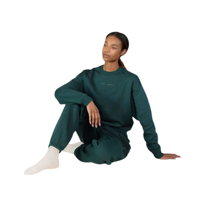 A person with curly hair models the Cozy Earth Women's CityScape Crewneck and matching pants in light pink against a plain white backdrop. |Color:Peony