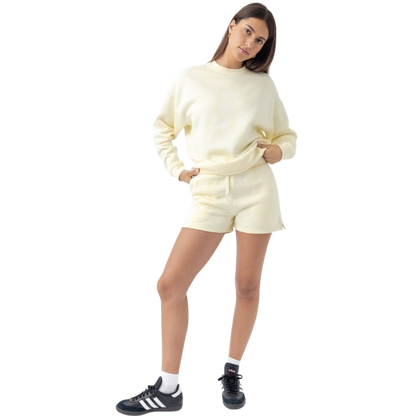 A person with curly hair models the Cozy Earth Women's CityScape Crewneck and matching pants in light pink against a plain white backdrop. |Color:Peony