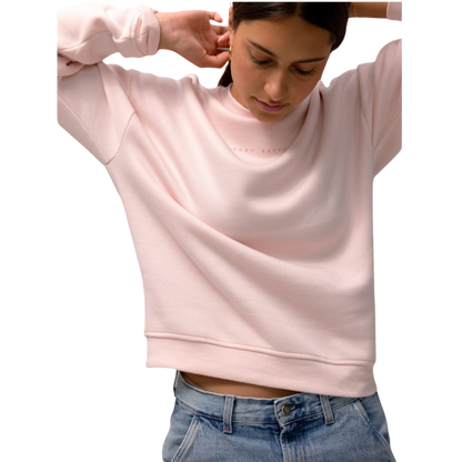 A person with curly hair models the Cozy Earth Women's CityScape Crewneck and matching pants in light pink against a plain white backdrop. |Color:Peony