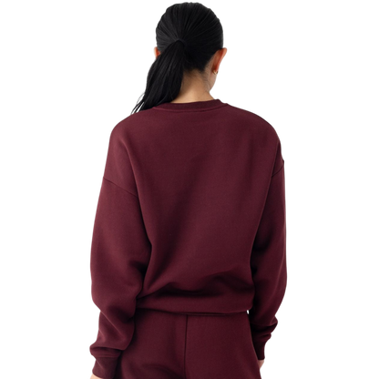 A person with curly hair models the Cozy Earth Women's CityScape Crewneck and matching pants in light pink against a plain white backdrop. |Color:Peony