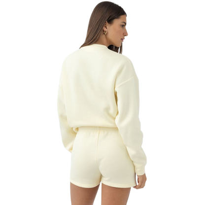 A person with curly hair models the Cozy Earth Women's CityScape Crewneck and matching pants in light pink against a plain white backdrop. |Color:Peony