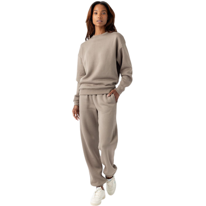 A person with curly hair models the Cozy Earth Women's CityScape Crewneck and matching pants in light pink against a plain white backdrop. |Color:Peony