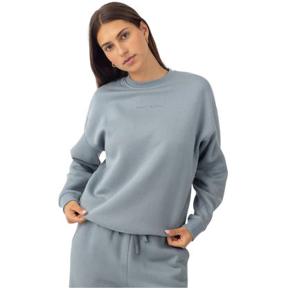 A person with curly hair models the Cozy Earth Women's CityScape Crewneck and matching pants in light pink against a plain white backdrop. |Color:Peony