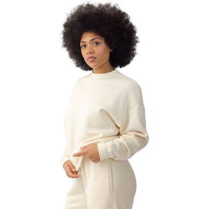 A person with curly hair models the Cozy Earth Women's CityScape Crewneck and matching pants in light pink against a plain white backdrop. |Color:Peony