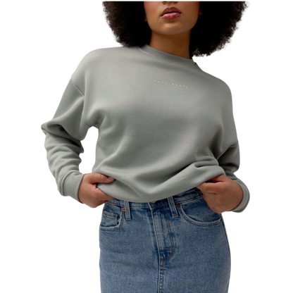 A person with curly hair models the Cozy Earth Women's CityScape Crewneck and matching pants in light pink against a plain white backdrop. |Color:Peony