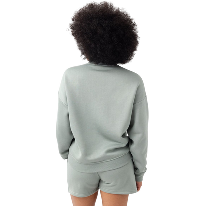 A person with curly hair models the Cozy Earth Women's CityScape Crewneck and matching pants in light pink against a plain white backdrop. |Color:Peony