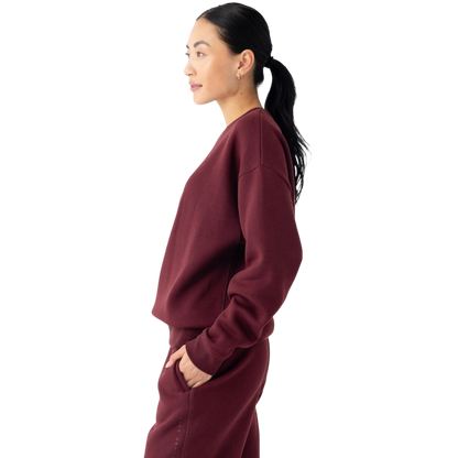 A person with curly hair models the Cozy Earth Women's CityScape Crewneck and matching pants in light pink against a plain white backdrop. |Color:Peony