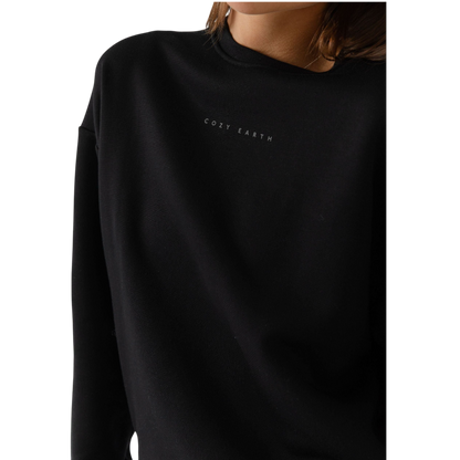 A person with curly hair models the Cozy Earth Women's CityScape Crewneck and matching pants in light pink against a plain white backdrop. |Color:Peony