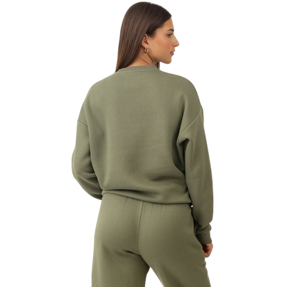 A person with curly hair models the Cozy Earth Women's CityScape Crewneck and matching pants in light pink against a plain white backdrop. |Color:Peony