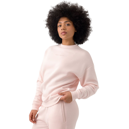 A person with curly hair models the Cozy Earth Women's CityScape Crewneck and matching pants in light pink against a plain white backdrop. |Color:Peony
